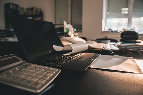 laptop and calculator on messy desk